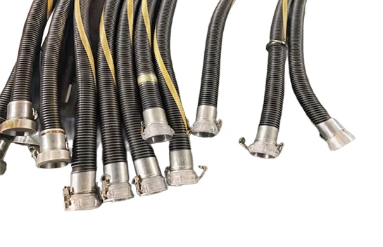 Multiple black fuel oil suction and discharge flexible composite hoses with fittings placed on the ground