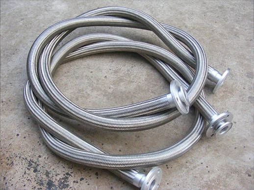 A braided metal hose with a flange joint placed on the ground